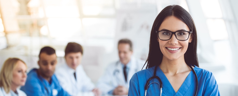 Nurse wearing glasses smiling in the foreground