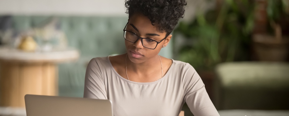 Woman with glasses looking down at a laptop computer